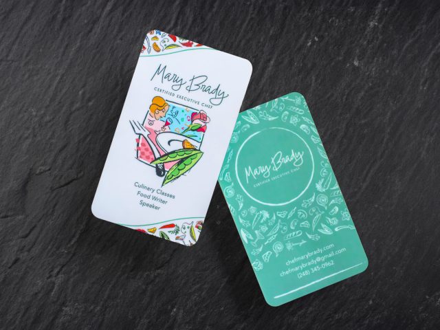 Mary Brady business card, front and back, laying on a slate table.
